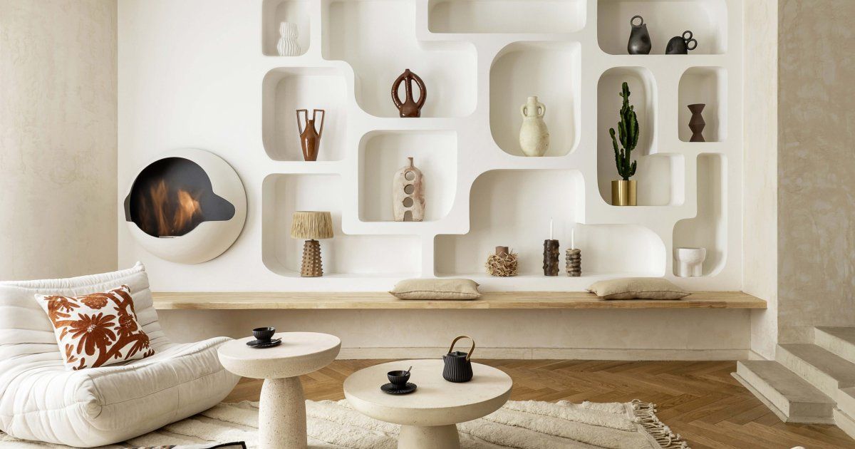Salon aux murs blancs avec une bibliothèque de niches arrondies en plâtre